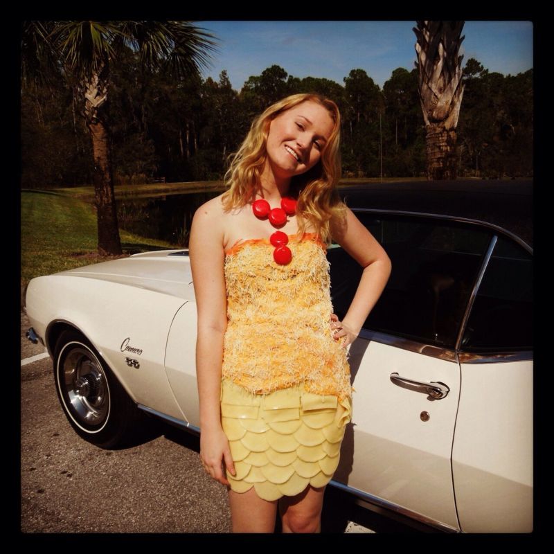 Девушки, одетые в сыр, фотографируются на фоне старых тачек