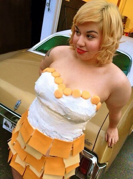 Девушки, одетые в сыр, фотографируются на фоне старых тачек