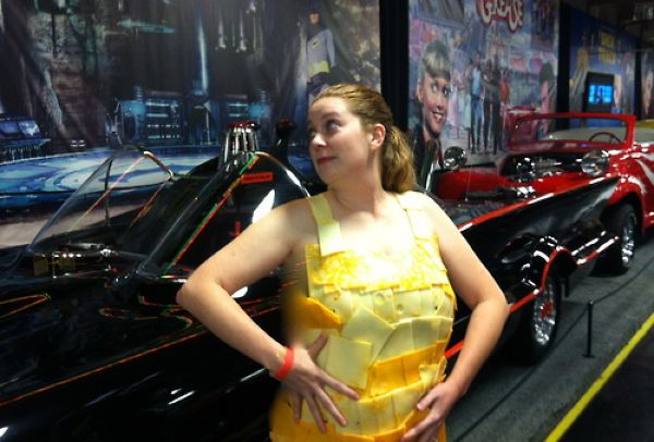 Девушки, одетые в сыр, фотографируются на фоне старых тачек