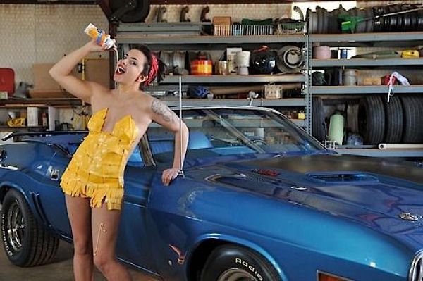 Девушки, одетые в сыр, фотографируются на фоне старых тачек